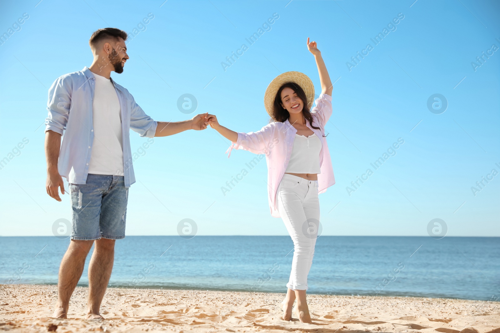 Photo of Happy young couple walking on beach near sea. Honeymoon trip