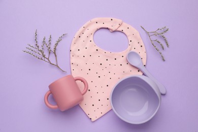 Flat lay composition with baby feeding accessories and bib on violet background