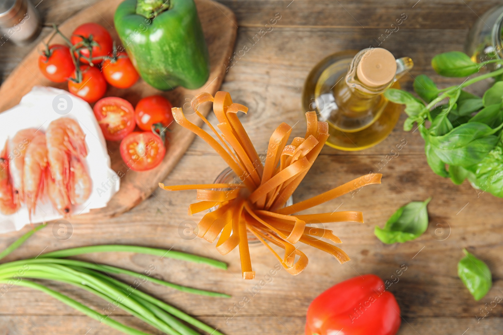 Photo of Uncooked buckwheat noodles and fresh ingredients on wooden table, flat lay