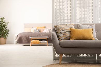 Comfortable sofa with different pillows in stylish room interior. Space for text