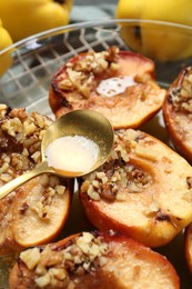 Photo of Pouring tasty honey onto baked quinces in bowl on table, closeup