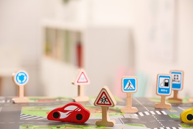 Set of wooden road signs and car indoors, closeup. Children's toys