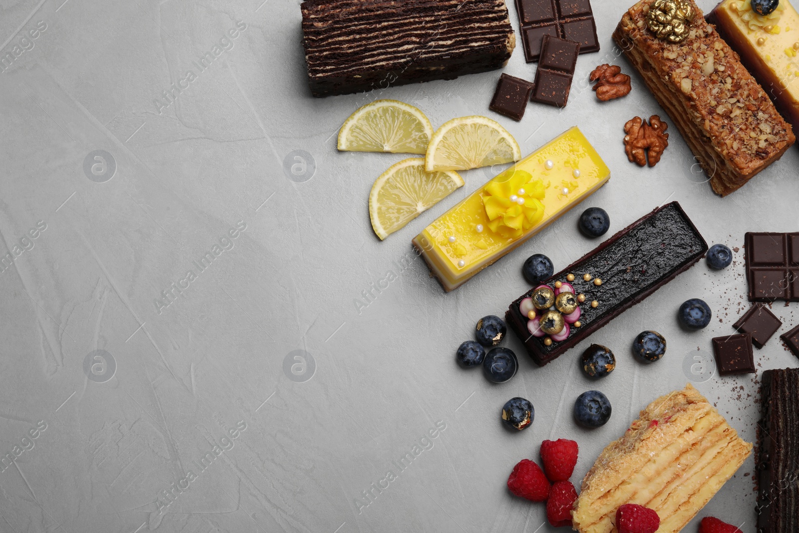 Photo of Flat lay composition with different tasty cakes on light grey table. Space for text