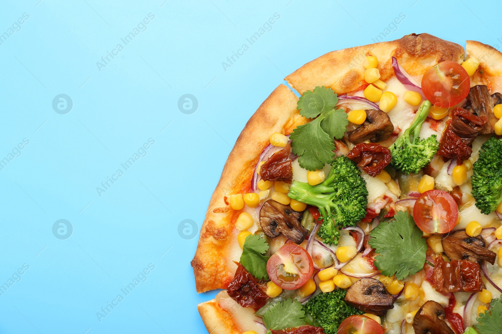 Photo of Delicious vegetarian pizza with mushrooms, vegetables and parsley on light blue background, top view. Space for text