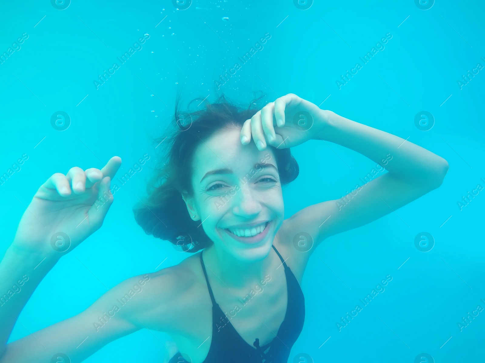 Photo of Beautiful young woman swimming in pool, underwater view