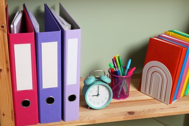 Photo of Colorful binder office folders and stationery on shelving unit indoors