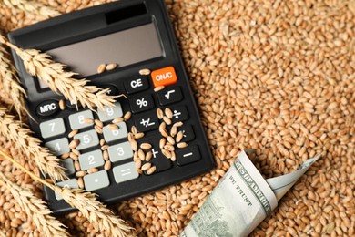 Photo of Dollar banknote, calculator and wheat ears on grains, above view. Agricultural business