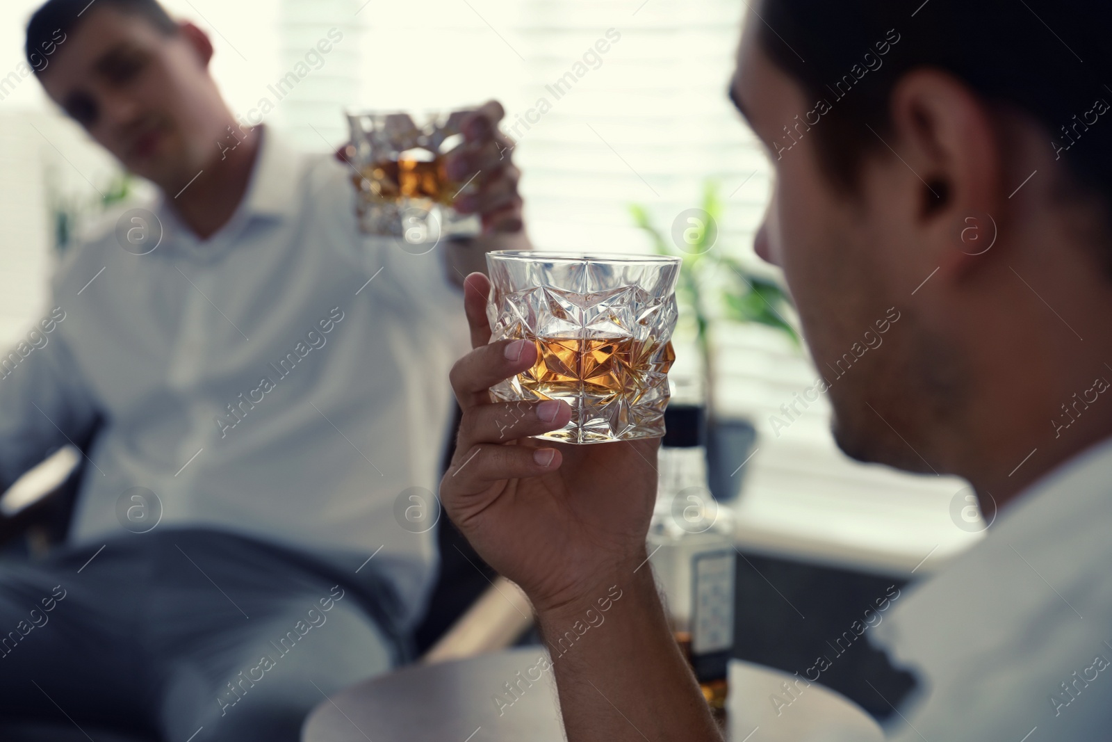Photo of Young men drinking whiskey together at home