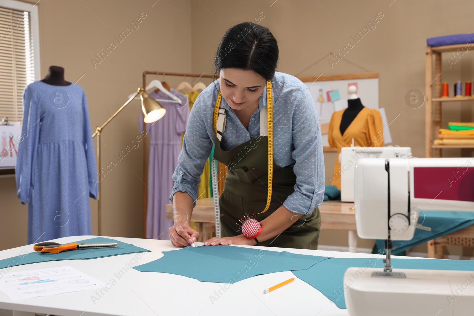 Photo of Dressmaker marking fabric with chalk in workshop