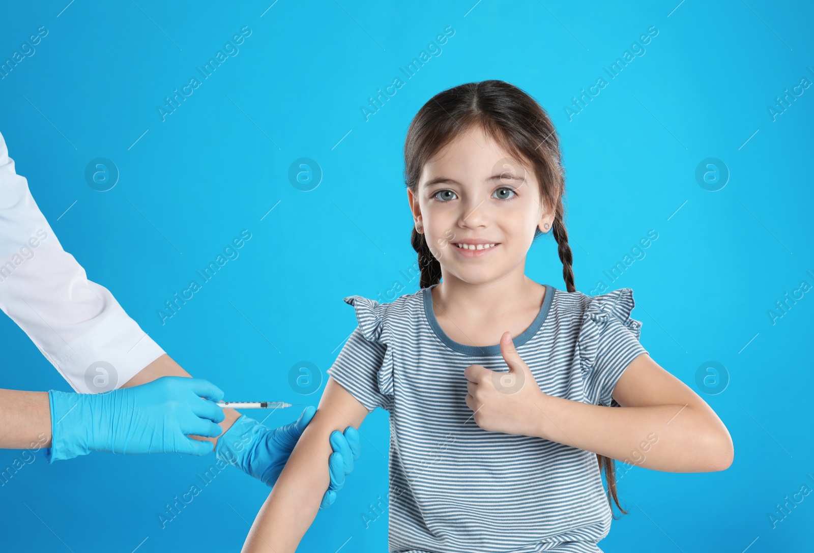 Photo of Doctor vaccinating little child on light blue background