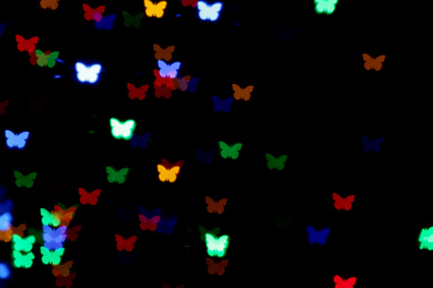 Blurred view of butterfly shaped lights on black background. Bokeh effect