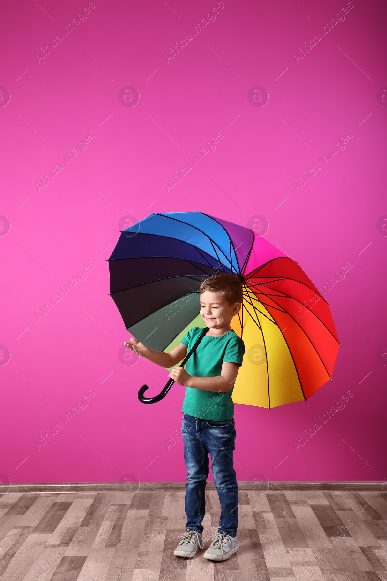 Photo of Little boy with rainbow umbrella near color wall