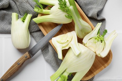 Fresh raw fennel bulbs and knife on white table, flat lay