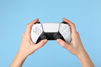 Photo of Woman using game controller on light blue background, closeup