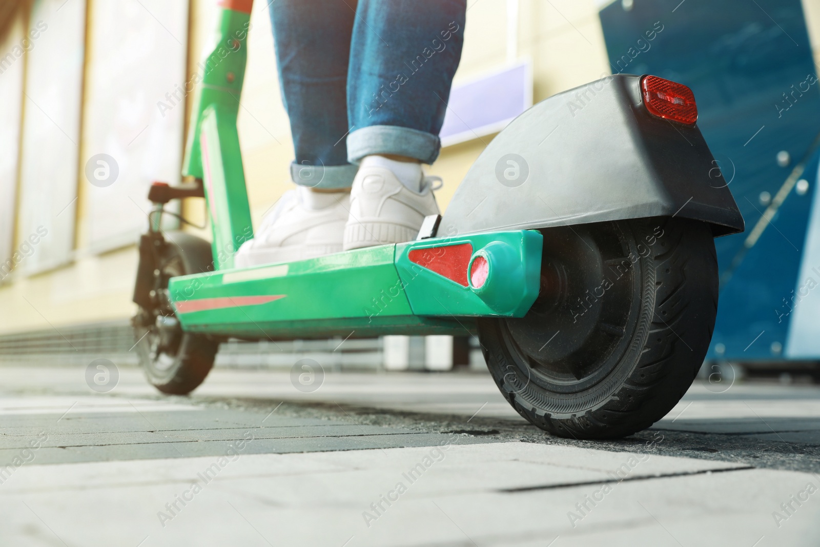 Photo of Woman riding modern electric kick scooter outdoors, closeup