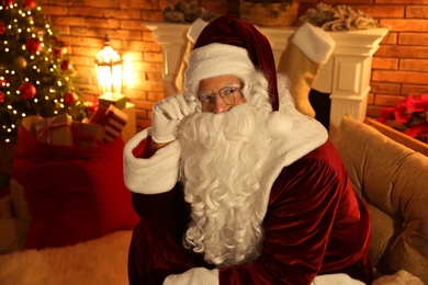 Photo of Santa Claus with glasses in festively decorated room