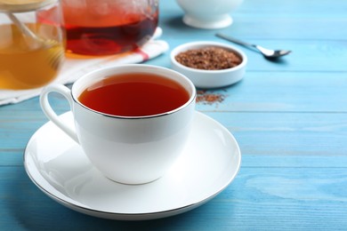 Freshly brewed rooibos tea on light blue wooden table. Space for text