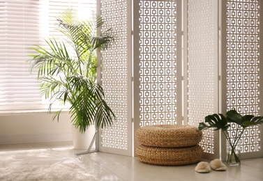 Stylish room interior with white folding screen and plants