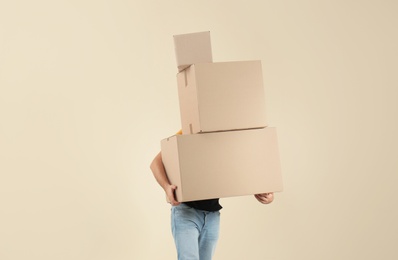 Young man carrying carton boxes on color background. Posture concept