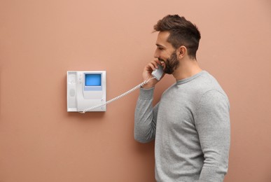 Man with handset answering intercom call indoors