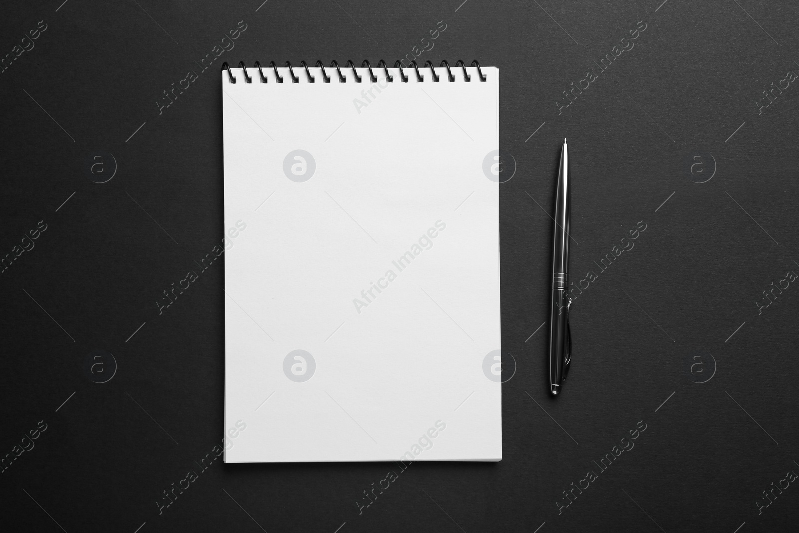 Photo of Notebook and pen on black background, top view