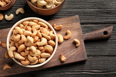 Bowl with cashew nuts on wooden table, flat lay. Space for text