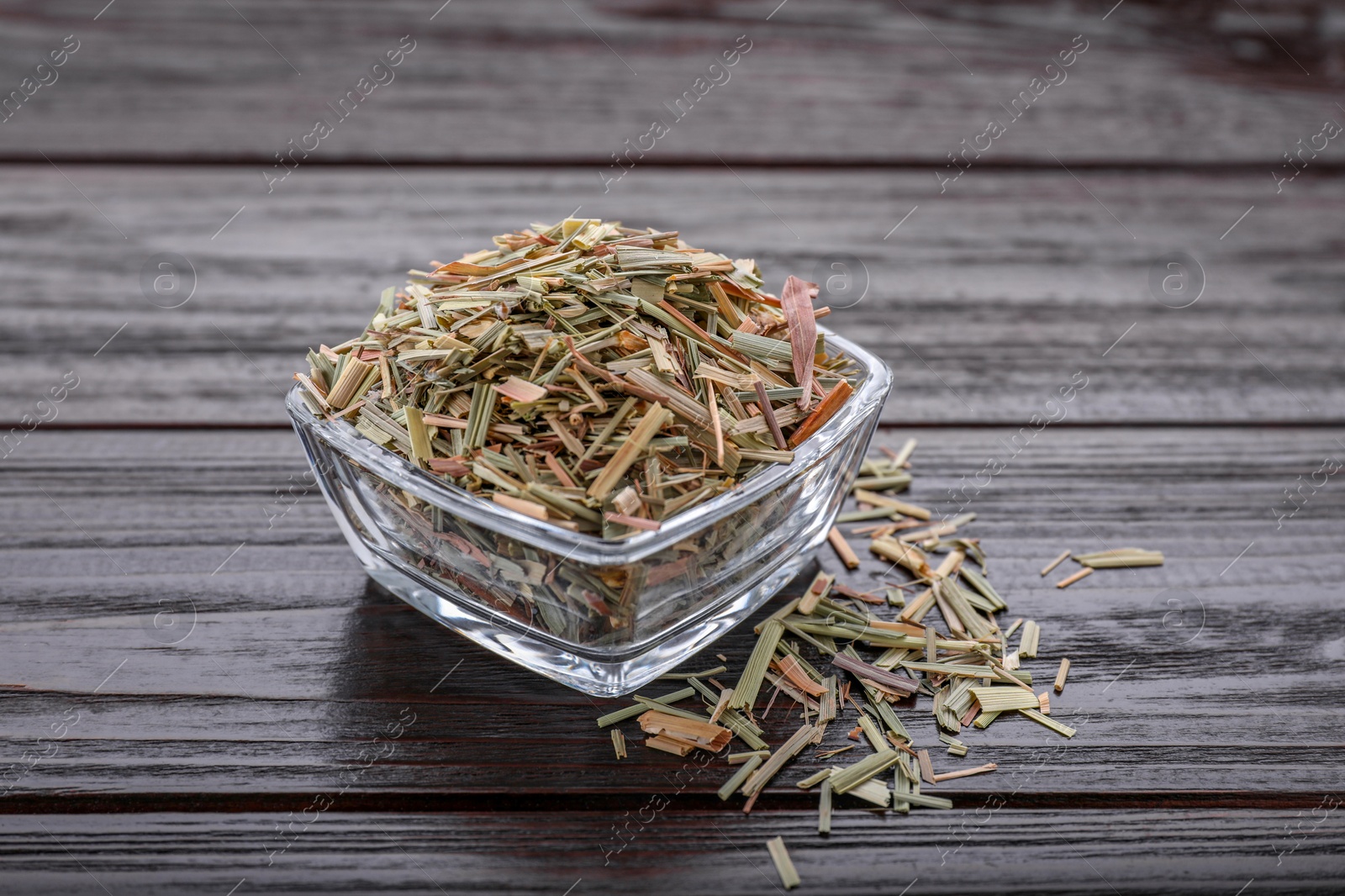 Photo of Glass bowl with aromatic dried lemongrass on wooden table