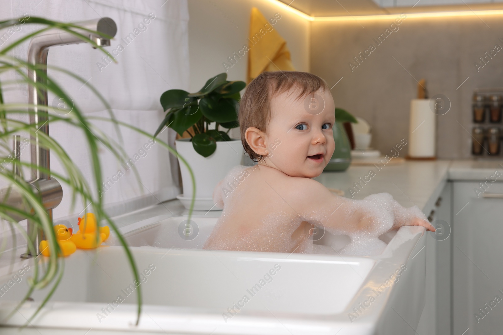 Photo of Cute little baby bathing in sink at home