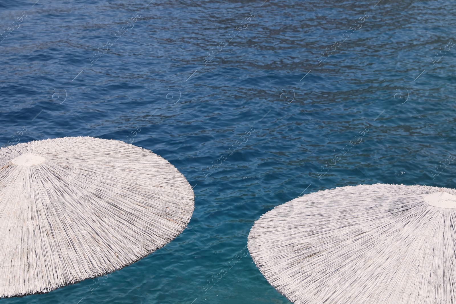 Photo of Beautiful straw umbrellas near sea on sunny day