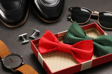 Photo of Stylish color bow ties, sunglasses, shoes, wristwatch and cufflinks on grey background