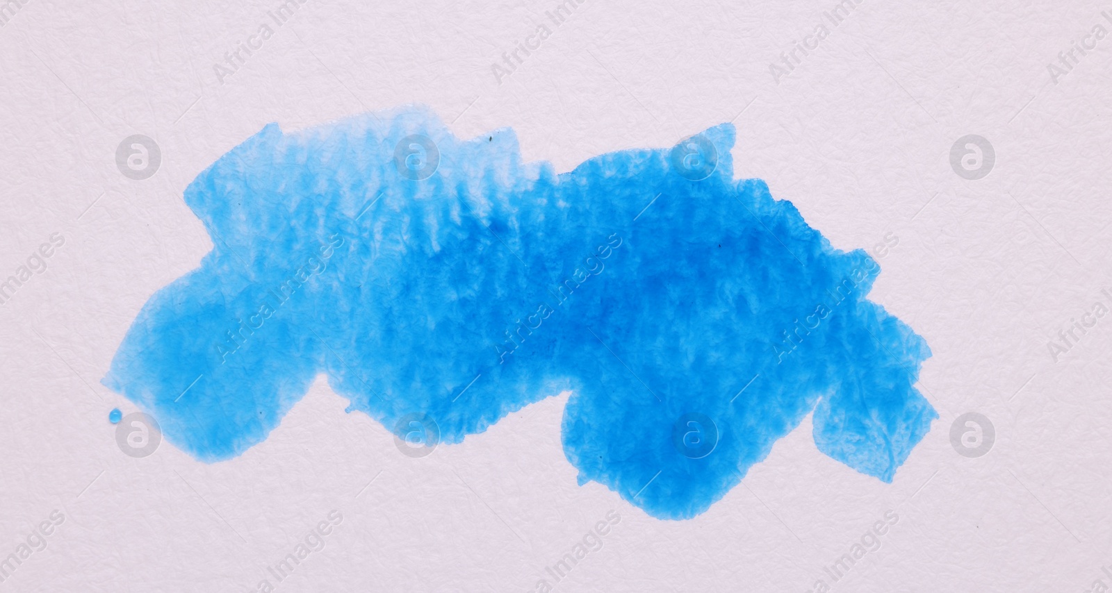 Photo of Blot of blue watercolor paint on white paper, top view