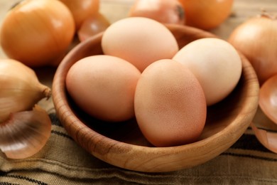 Easter eggs painted with natural dye in wooden bowl on table, closeup