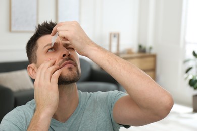 Photo of Man using drops for eyes at home