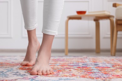 Photo of Woman standing on carpet with pattern at home, closeup. Space for text