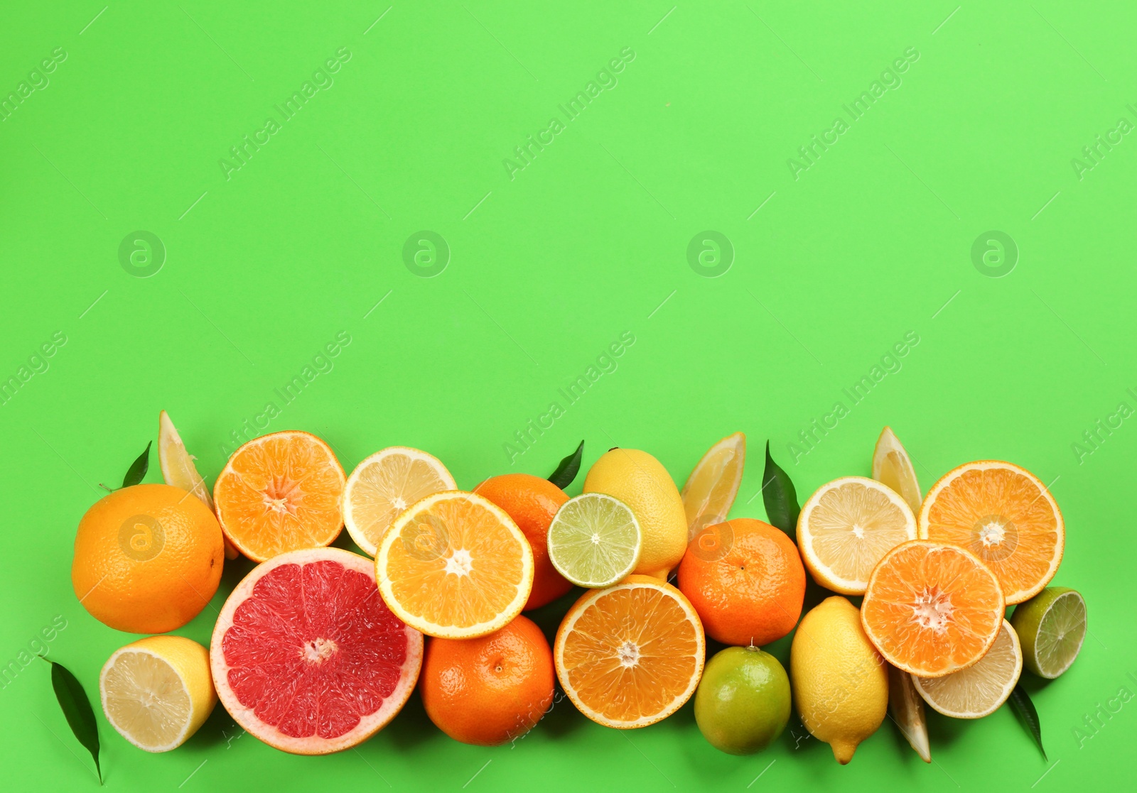 Photo of Flat lay composition with tangerines and different citrus fruits on green background. Space for text