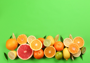 Flat lay composition with tangerines and different citrus fruits on green background. Space for text