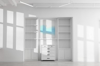 Photo of Shelving unit, chest of drawers and shadows on wall