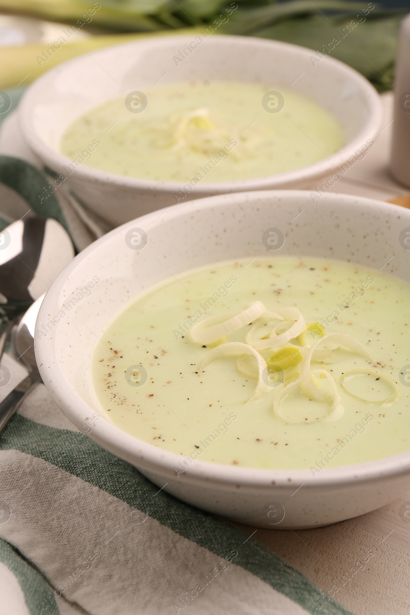 Photo of Bowls of tasty leek soup on table, closeup