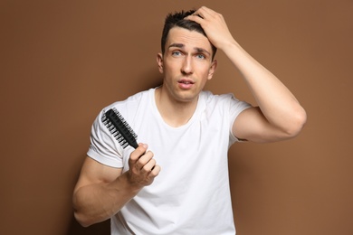 Young man with hair loss problem on color background