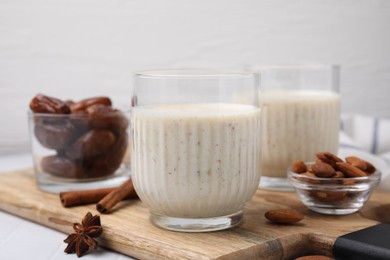 Glass of delicious date smoothie, dried fruits, spices and nuts on table