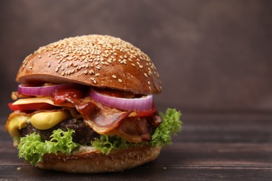 Photo of Delicious burger with bacon, patty and vegetables on wooden table, closeup. Space for text