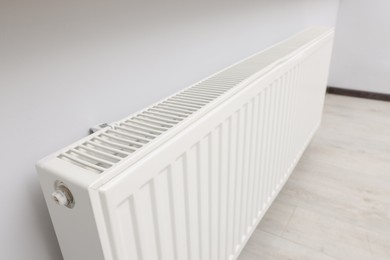 Photo of Modern radiator on white wall in room, closeup. Central heating system