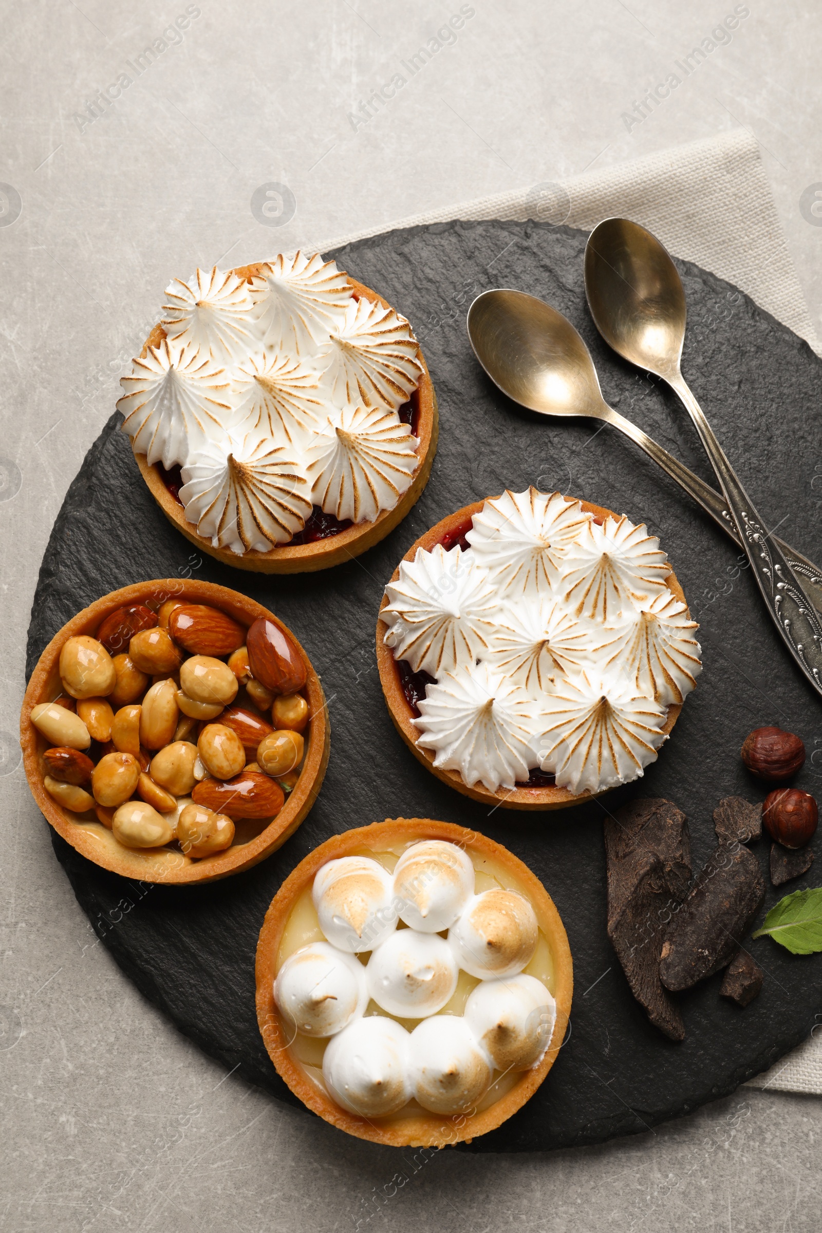 Photo of Many different tartlets served on grey table, top view. Delicious dessert