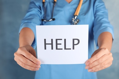 Doctor holding card with word Help in hands, closeup