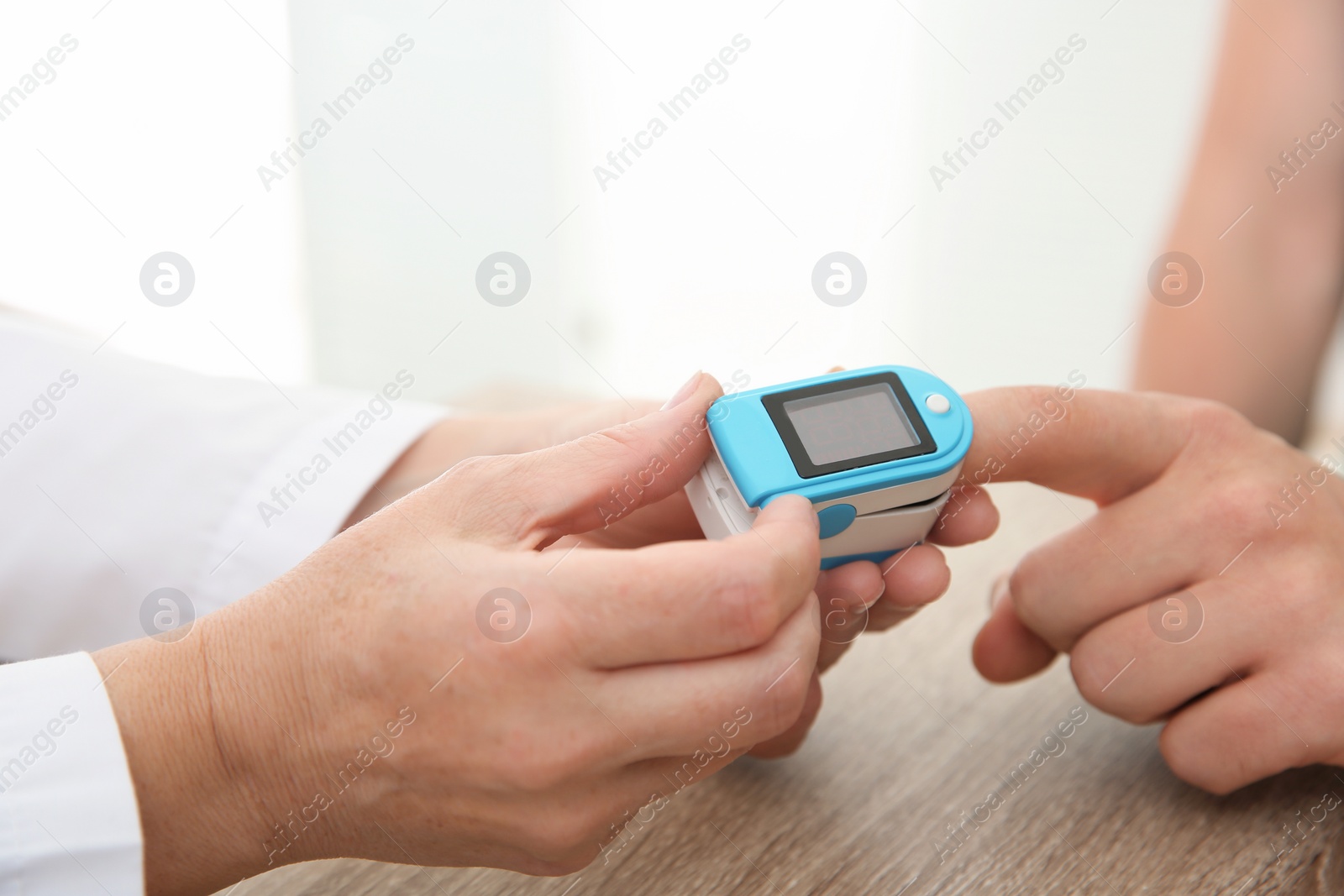 Photo of Doctor checking man's pulse with medical device in hospital, closeup