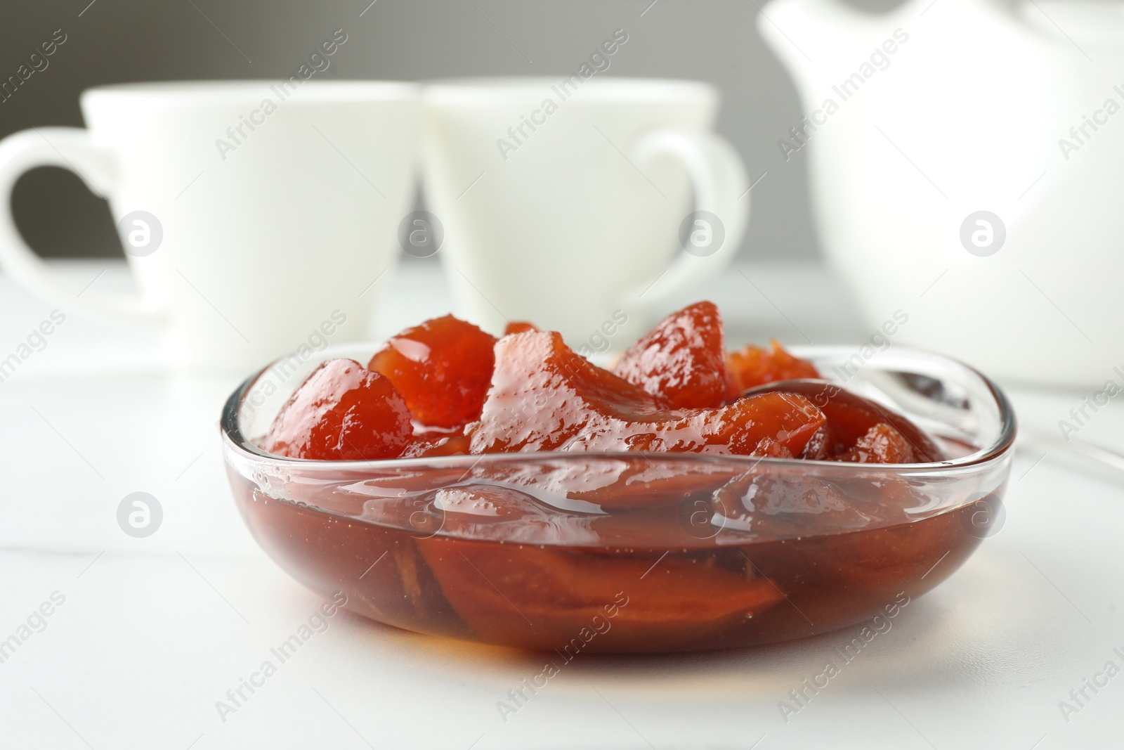 Photo of Quince jam in glass bowl served to tea on white table, closeup