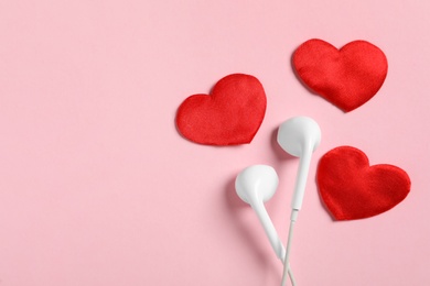 Photo of Modern earphones and red hearts on pink background, flat lay with space for text. Listening love music songs