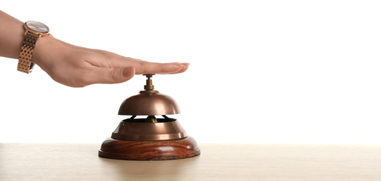 Photo of Woman ringing hotel service bell at wooden table