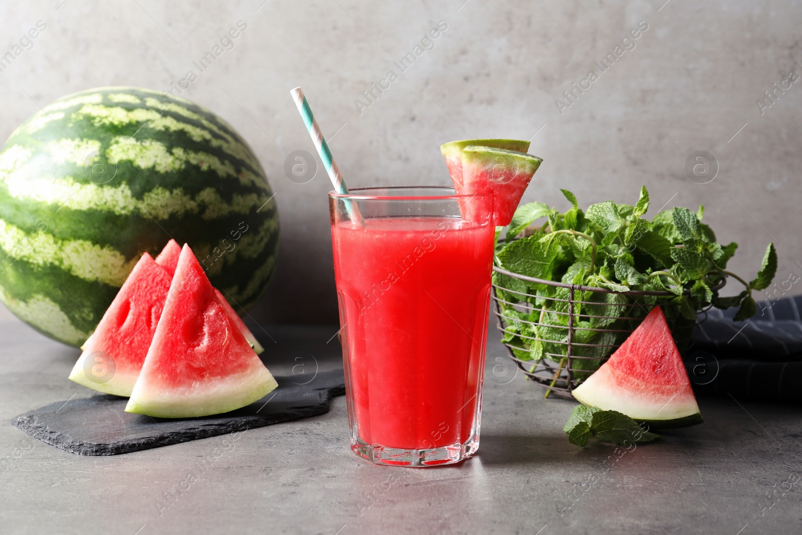 Photo of Summer watermelon drink in glass and sliced fruit on table