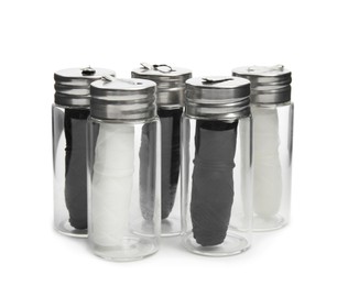 Rolls of natural organic dental floss in jars on white background